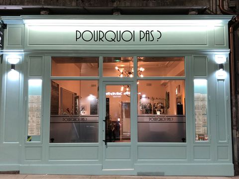 La devanture céladon du restaurant Pourquoi Pas, rue Monge à Dijon, éclairée à la nuit tombée